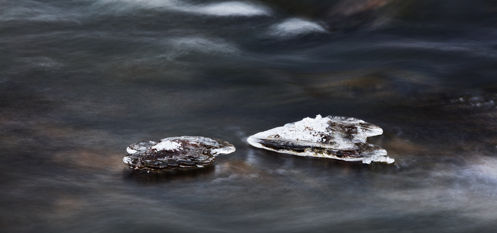 Mit Eis überzogene Steine in einem Fluss