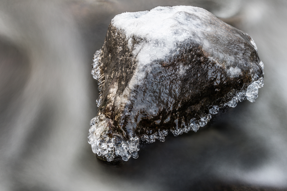 Mit Eis überzogene Steine in einem Fluss