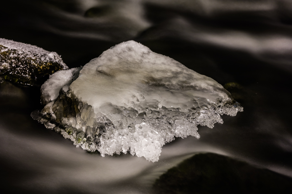 Mit Eis überzogene Steine in einem Fluss