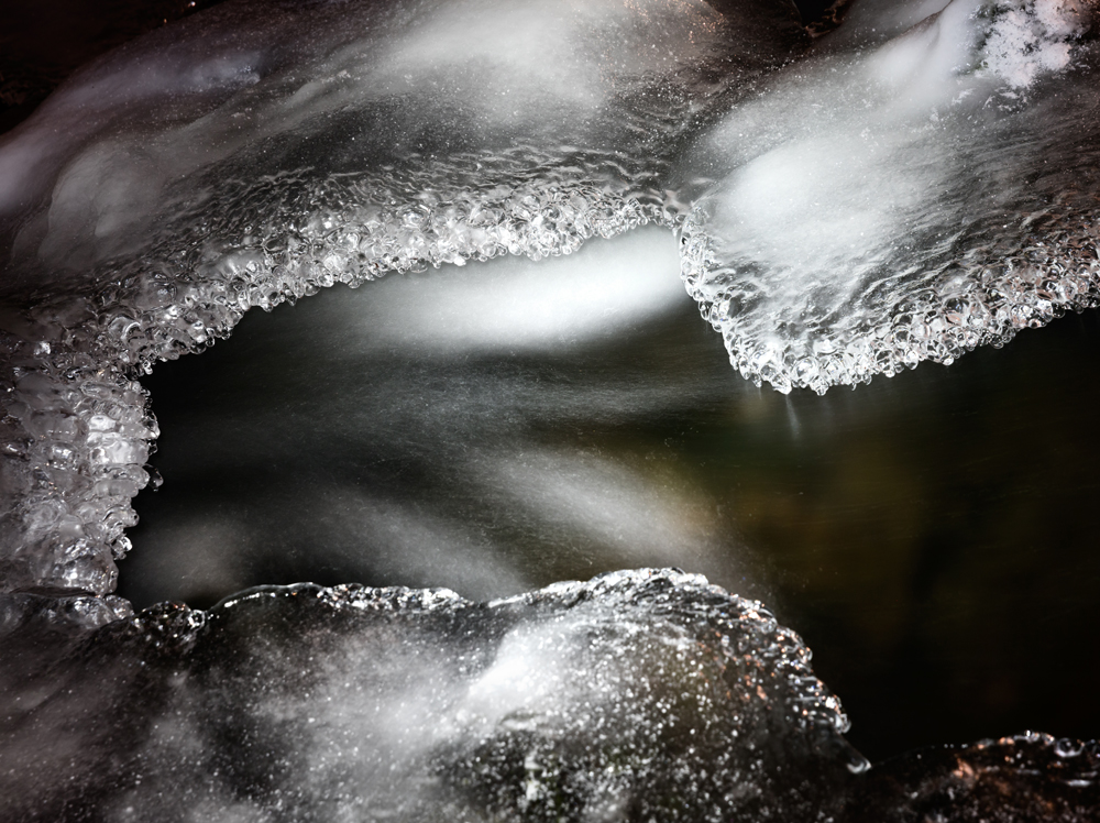 Mit Eis überzogene Steine in einem Fluss