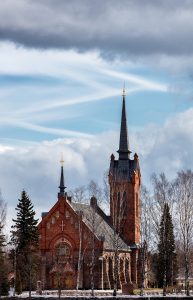 Kirche von Eura von rechts beschienen vor teilweise bewölktem Himmel
