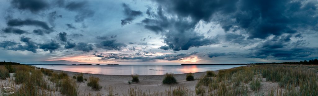 Panorma eines Strandes zur Blauen Stunde mit Wolken am Himmel