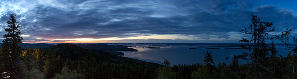 Blick über eine große Wasserfläche von einem Steinhügel aus zur Blauen Stunde