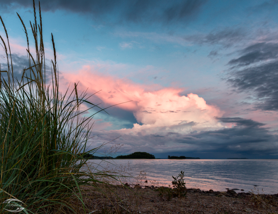 Rot belechtete Gewitterwolken über einem See