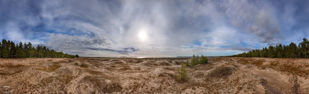 Panorma eines Strandes mit der untergehenden Sonne über dem Horizont