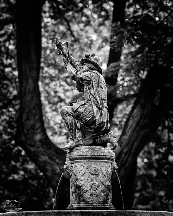 Bild einer Statue eines Bogenschützen vor Bäumen