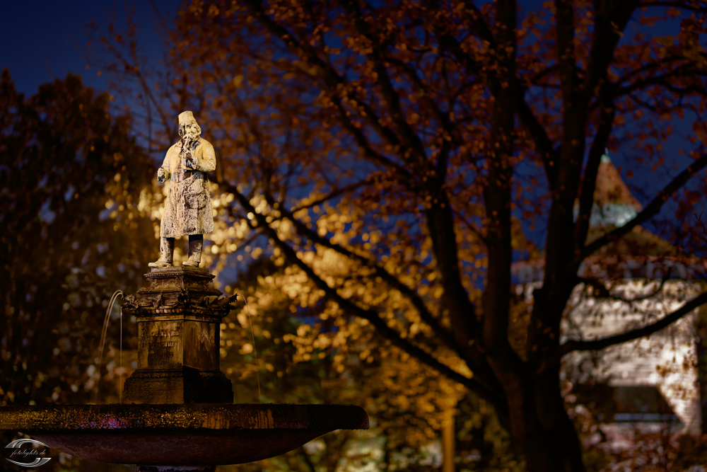 Statue hinter einem Baum bei Nacht