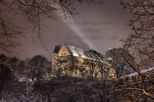 Bild der Kaiserburg durch verschneites Geäst mit dem Schriftzug Frohe Weihnachten und ein gesundes neues Jahr im Himmel