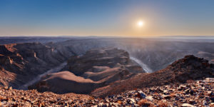 Blick über einen Cayon mit der Sonne nahe dem Horizont