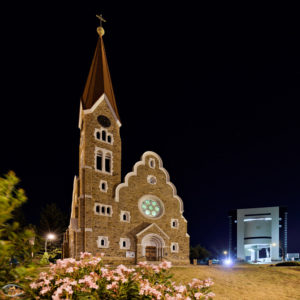 Kirche und ein modernes Gebäude im Hintergrund bei Nacht