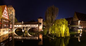 Bild vom Weinstadl und zweier Bäume an einem Fluss bei Nacht