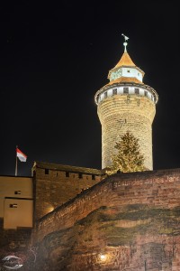 Bild des Sinnwellturmes mit der Burgmauer im Vordergrund. Auf die Burgmauer sind Neujahrsgrüße projeziert